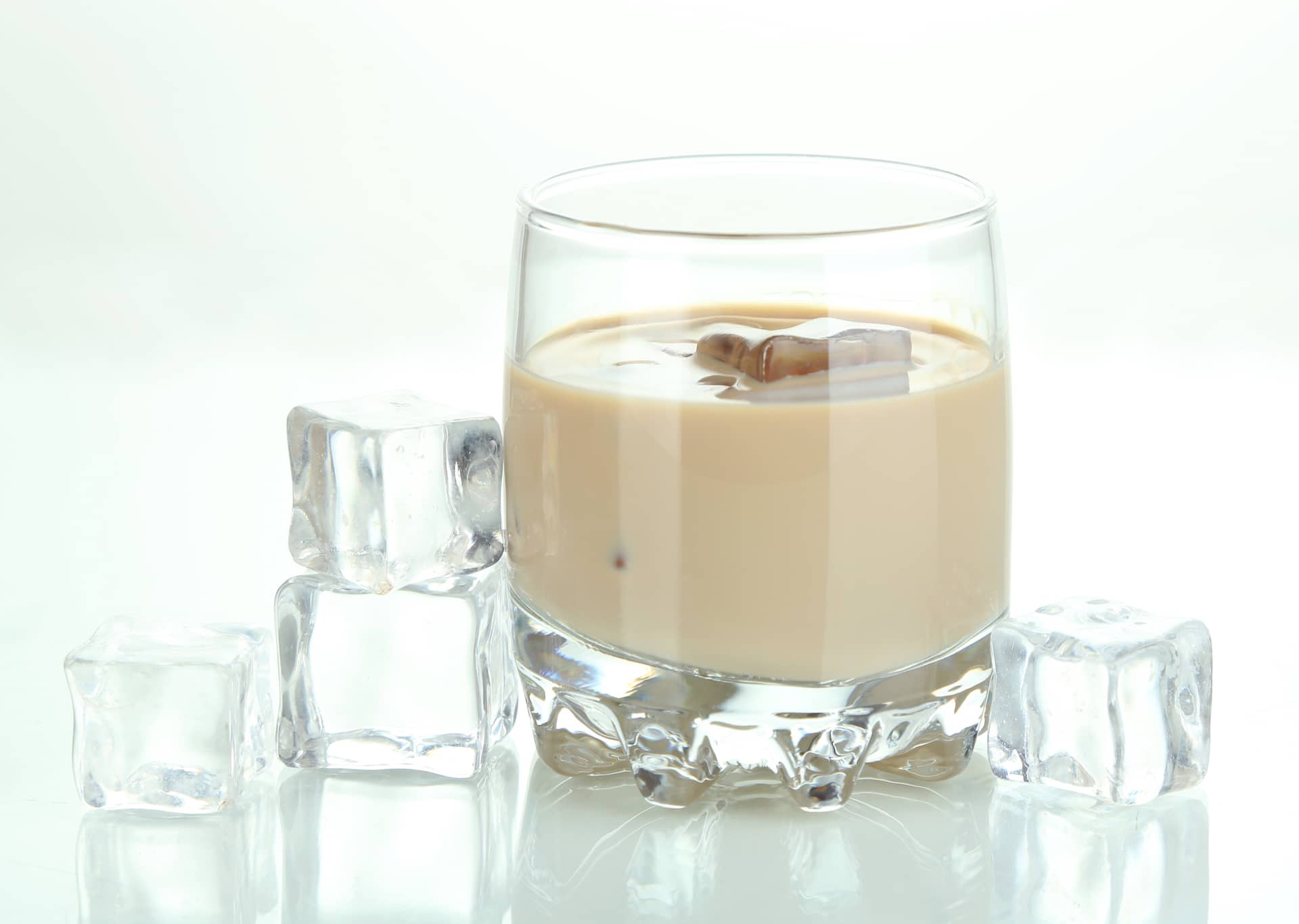 Almond milk in glass with liquor isolated on white