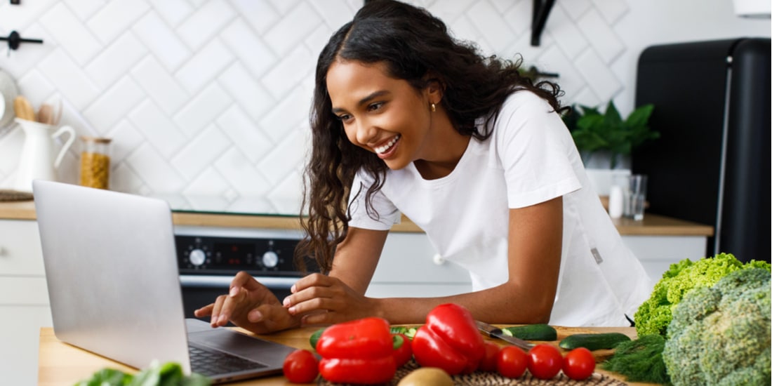 Woman working at a computer with healthy veggies around her