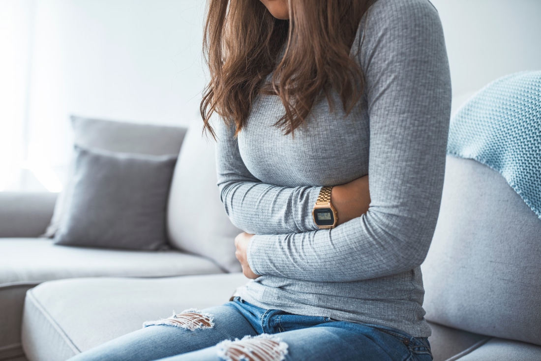 woman sitting holding her tummy, needing foods to help poop