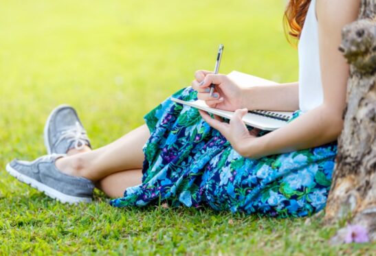 Woman sitting by a tree journaling