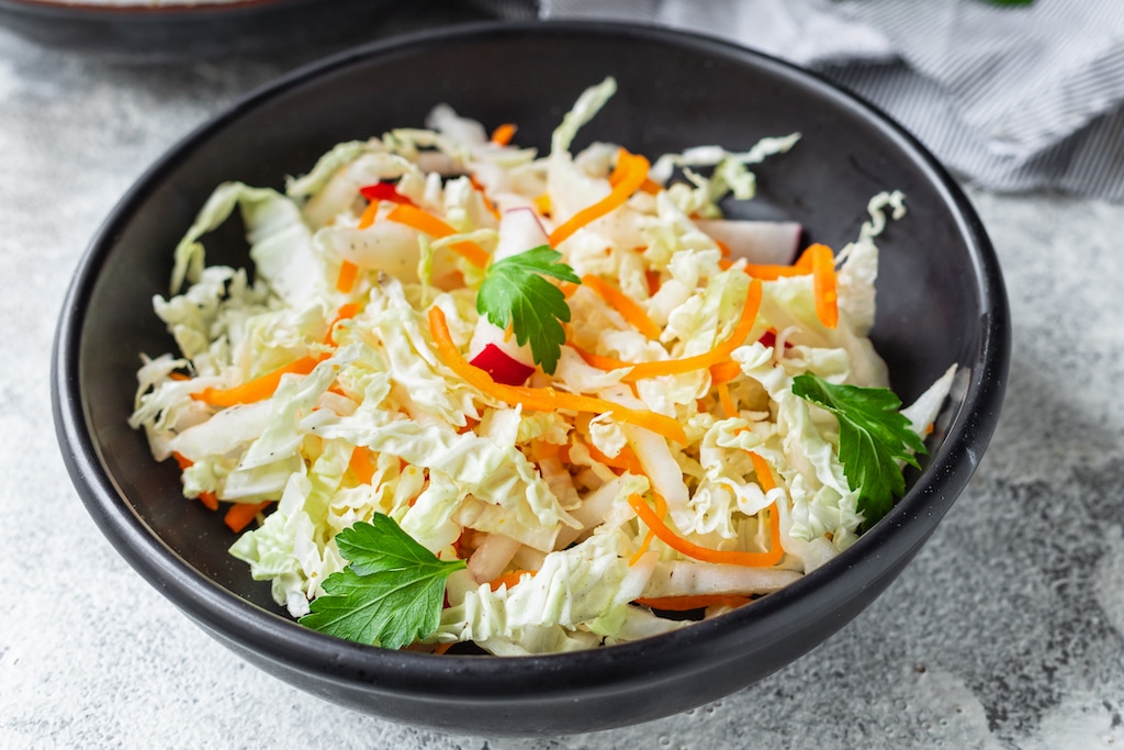Mixed shredded cabbage, sliced carrot, radish, pepper in a bowl