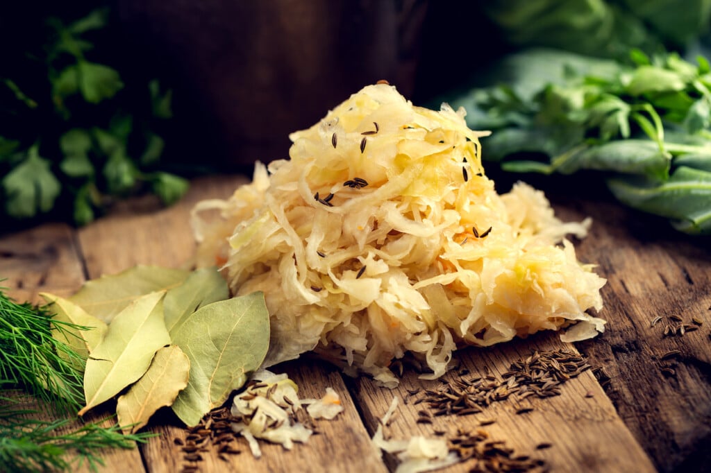 Sauerkraut as the best probiotic in the world. Homemade sauerkraut pickling. Sauerkraut on a wooden table with green leaves as background
