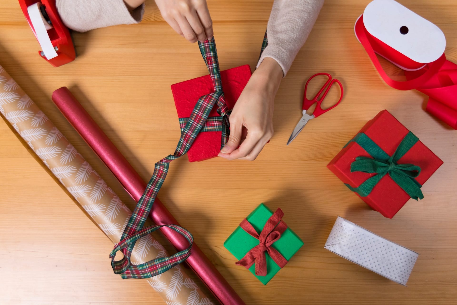 Women's hands prepare boxed gifts for the holiday season. 