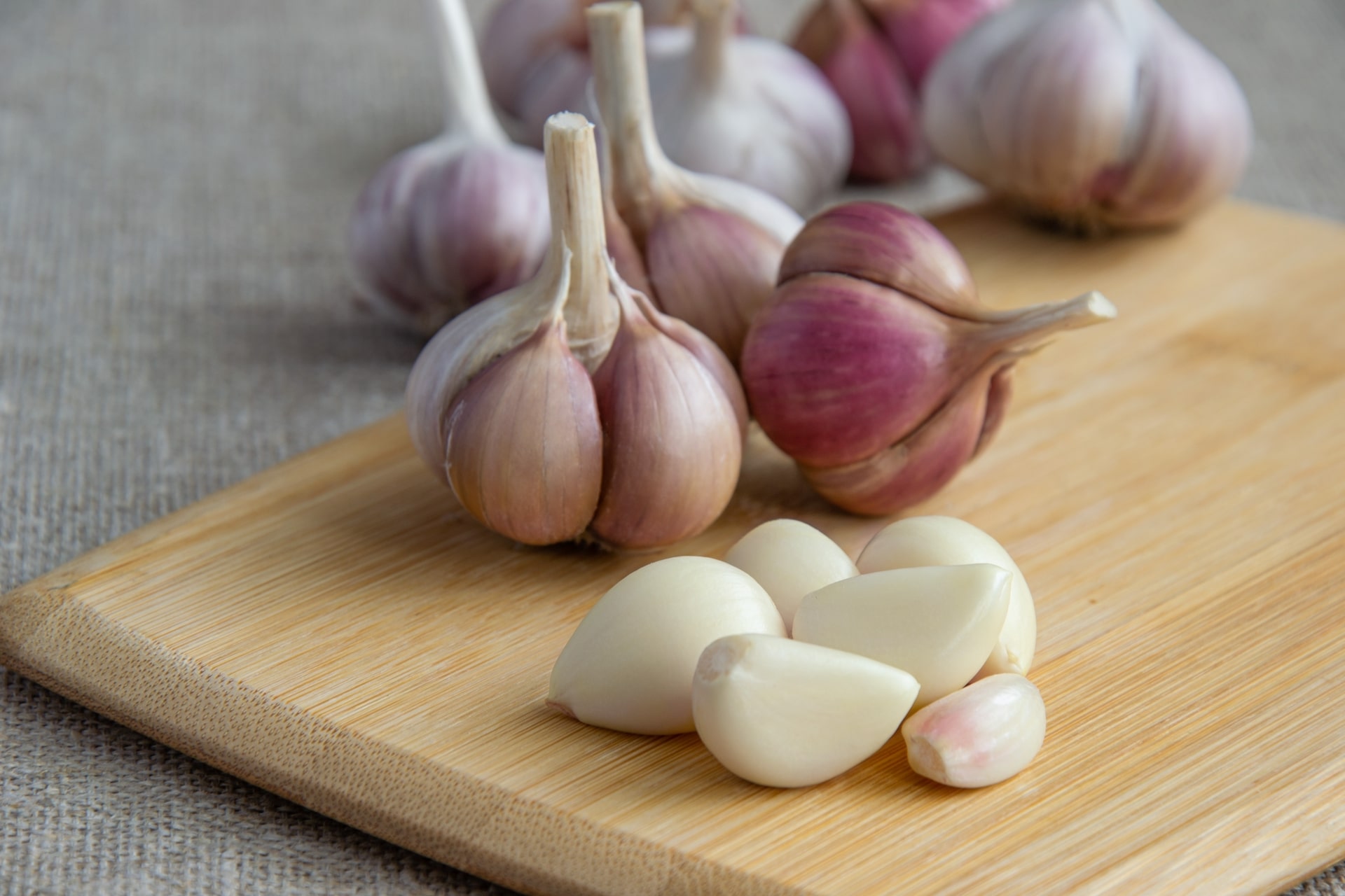 Garlic bulbs on top of a wooden board with garlic blur background.