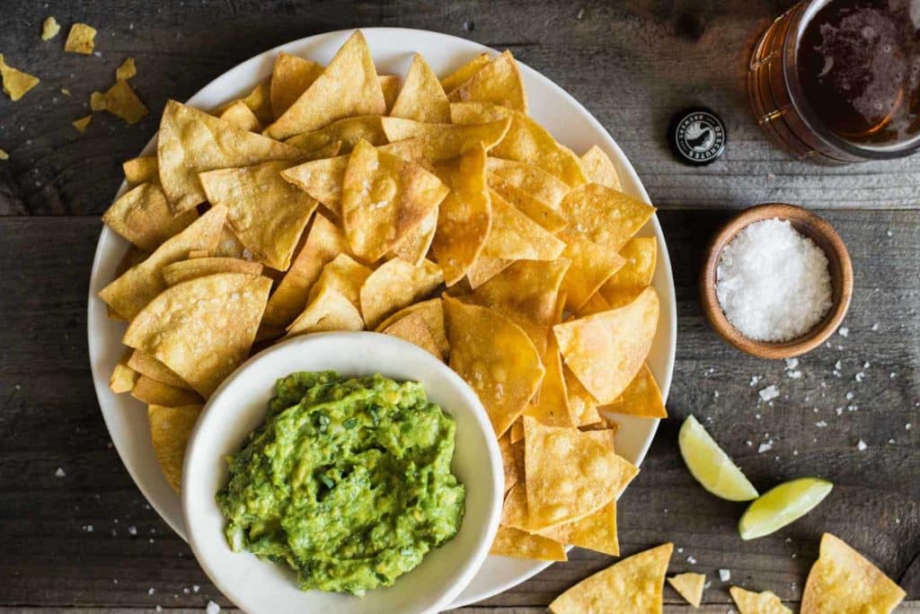 Baked Tortilla Chips and Guacamole on a wooden table 