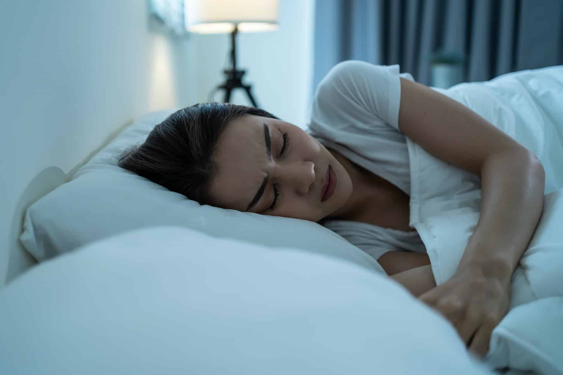 Woman, looking tired and stressed out lying on bed asleep.